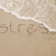 The word ‘stress’ is carved into the sand. The waves are slowly beginning to cover the letters, beginning with the last ‘s.’